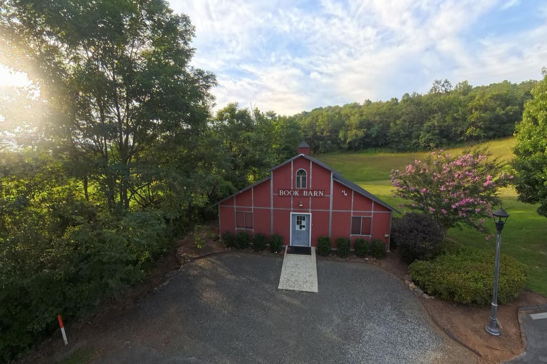 The Book Barn, a red barn with BOOK BARN painted across the gable, beside a flowering crape myrtle.
