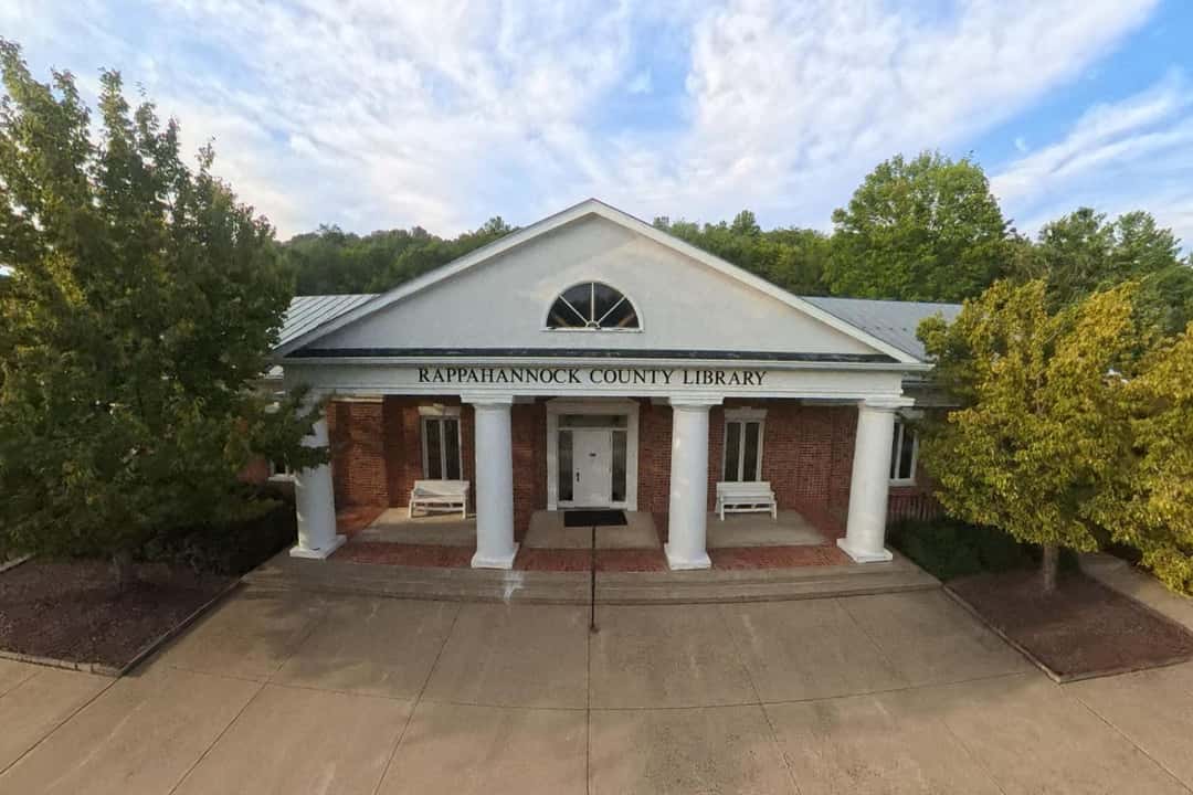 The front of the Rappahannock County Library, seen straight on between two trees.